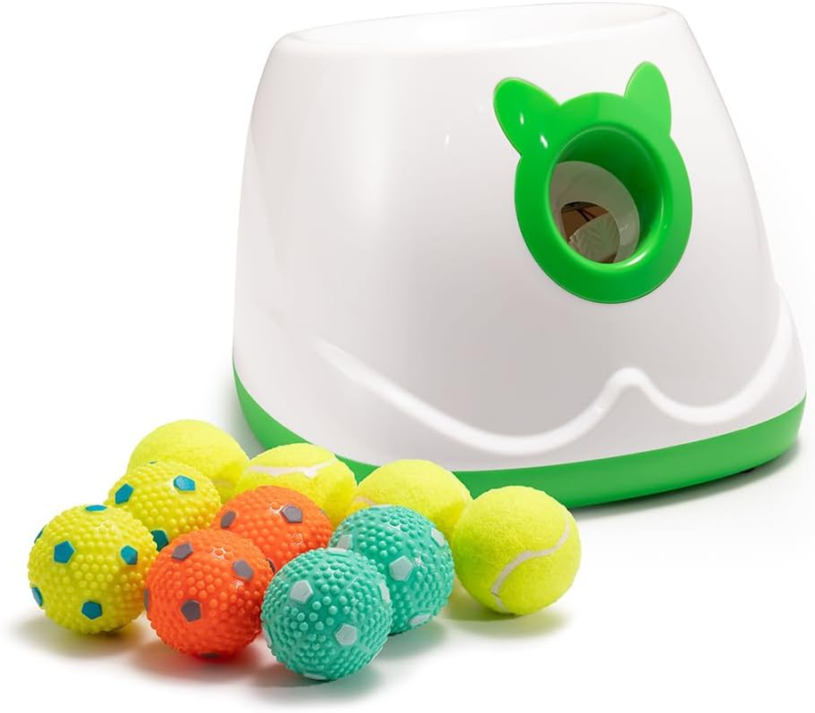 White and green automatic dog ball launcher displayed with ten assorted 2-inch tennis and textured latex balls.