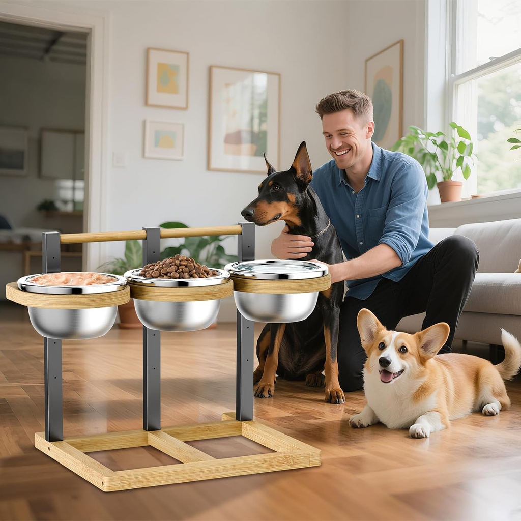 Man with two dogs interacting with a raised pet feeding station in a home setting.