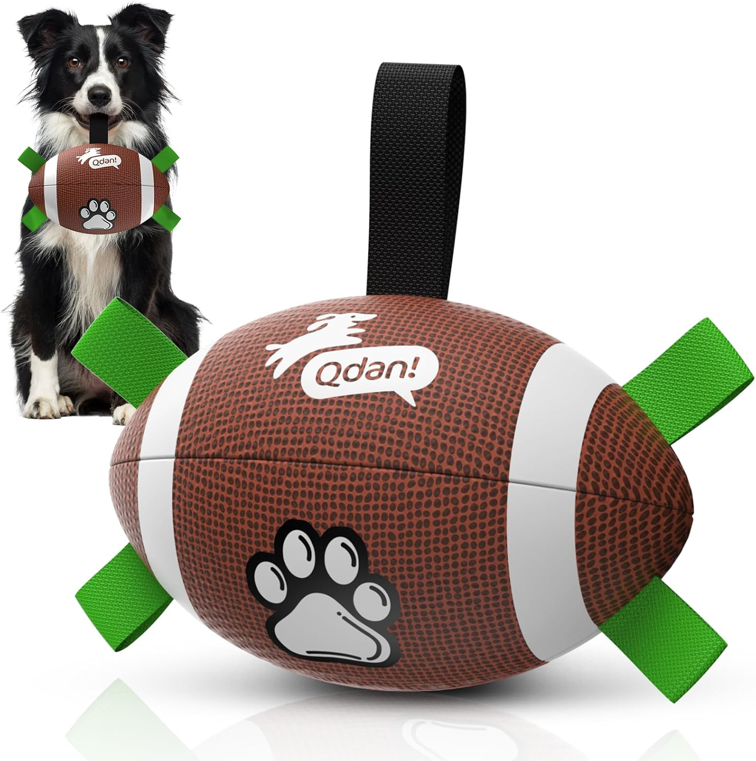 A dog-shaped football pet toy with green ribbon tails and a black hanging loop, shown in front of a black-and-white dog holding a similar toy. The toy has a brown textured surface with white stripes, a white dog graphic, a paw print, and the visible brand name Qdan! on the front.